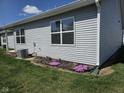 Side view of a house with vinyl siding, a manicured lawn, and a small flower garden at 1615 Capra Ct, Beech Grove, IN 46107