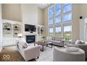 Bright living room with soaring ceilings, fireplace, built-in shelving, and oversized windows with backyard view at 20251 Dayspring Ct, Noblesville, IN 46062