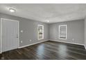 A spacious living room featuring gray walls, wood flooring, and natural light from two windows at 3343 N Drexel Ave, Indianapolis, IN 46218