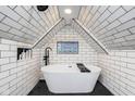Bright bathroom boasting a modern tub, skylight, white tile and black honeycomb tile flooring at 415 S Oxford St, Indianapolis, IN 46201