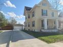 Side view of a yellow two-story home with a long driveway and detached garage at 509 E Columbus St, Martinsville, IN 46151