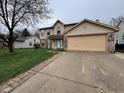 Traditional two-story home with a tan exterior, a two-car garage, and a brick-lined driveway at 5814 Lakefield Dr, Indianapolis, IN 46254