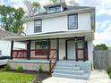 Charming two-story home with a covered front porch, black accents, and landscaped yard at 625 N Parker Ave, Indianapolis, IN 46201