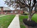 Inviting brick townhouse with a concrete walkway, set amongst a lush green lawn with mature trees at 914 Greenwood E Trl, Greenwood, IN 46142