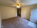 Cozy living room with neutral carpet, ceiling fan, and a bright front door, ready for personal touches at 914 Greenwood E Trl, Greenwood, IN 46142