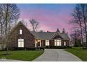 Elegant brick home with a curved driveway, bay windows, and lush landscaping under a vibrant sky at 10109 Fergus Ave, Carmel, IN 46032