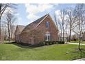 Side view of a brick home showcasing its well-kept lawn, trimmed bushes, and classic window shutters at 10109 Fergus Ave, Carmel, IN 46032