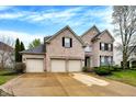 Charming two-story brick home featuring a three-car garage and manicured lawn at 12479 Autumn Gate Way, Carmel, IN 46033