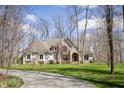 Elegant home features a stone facade, arched entryway with a red door, and a long driveway leading to the property at 23219 Marin Dr, Cicero, IN 46034