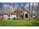 Stunning home boasts a lush green lawn, mature trees, and a welcoming front entrance with an arched doorway at 23219 Marin Dr, Cicero, IN 46034