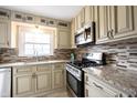 Bright kitchen features granite countertops, mosaic backsplash, stainless steel appliances, and ample cabinetry at 5735 Brouse Ave, Indianapolis, IN 46220
