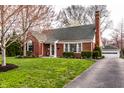 Beautifully maintained home with brick facade, mature trees, and a detached garage accessible by a paved driveway at 6041 Garver Rd, Indianapolis, IN 46208