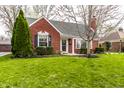 Quaint brick home with a well-kept lawn, decorative shutters, and mature landscaping at 6041 Garver Rd, Indianapolis, IN 46208
