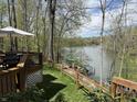 Wooden deck overlooking lake with table, chairs, and umbrella, surrounded by trees at 7809 S Solitude Ln, Trafalgar, IN 46181