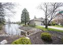Home featuring a beautiful lakeside view from the front yard, enhanced by mature trees and meticulous landscaping at 8075 N Cardinal W Cv, Indianapolis, IN 46256