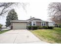 Charming one-story home with a two-car garage, a well-maintained lawn, and lush landscaping in a serene setting at 8075 N Cardinal W Cv, Indianapolis, IN 46256