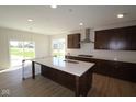 Open kitchen featuring an island with sink, quartz countertops, and dark wood cabinetry at 10543 Banyan Wood Ct, Indianapolis, IN 46239