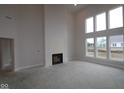 Living room featuring tall ceilings, modern fireplace, and large windows overlooking the backyard at 10543 Banyan Wood Ct, Indianapolis, IN 46239