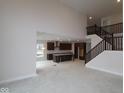Open-concept living room showcasing soaring ceilings, staircase, and a view into the kitchen at 10543 Banyan Wood Ct, Indianapolis, IN 46239