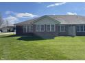 Spacious backyard featuring a well-maintained lawn and the rear view of a brick single-story home at 1623 Senior Ct, Shelbyville, IN 46176