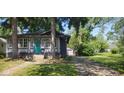 Delightful home with mature trees, a turquoise door, and a long driveway leading to a detached garage at 213 S Brittain Ave, Muncie, IN 47303