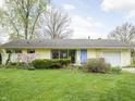 Single-story house featuring manicured front lawn and garden with mature trees and a colorful blue front door at 2816 Canterbury Ln, Indianapolis, IN 46220