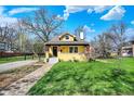 Inviting exterior of a yellow home with a beautifully landscaped front yard and blue skies at 3484 Birchwood Ave, Indianapolis, IN 46205