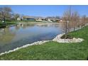 Picturesque view of a pond with a grassy shoreline and mature trees at 52 Spring Lake Ct, Trafalgar, IN 46181