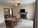 Inviting living room featuring a cozy fireplace, plush carpeting, and a stylish ceiling fan, perfect for relaxation and entertainment at 6005 Wingedfoot Ct, Indianapolis, IN 46254