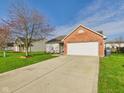 Well-maintained home with a brick accent, a spacious driveway, and a vibrant green lawn at 6233 Boulder Dr, Anderson, IN 46013