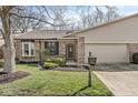 Charming brick home with a well-maintained lawn, mature tree, and attached two-car garage at 8433 Quail Hollow Rd, Indianapolis, IN 46260