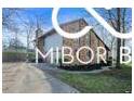 Beautiful home with a stone and siding exterior, a well-maintained driveway, and lovely landscaping at 8500 N Ravenwood Dr, Muncie, IN 47303