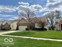 Charming single-story home featuring a well-manicured lawn, two-car garage, and inviting facade at 8875 Stonewick Way, Zionsville, IN 46077