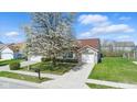 Well-maintained single Gathering home with green lawn, mature flowering tree, and brick facade garage at 10876 Bellflower Ct, Indianapolis, IN 46235