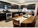 Cozy kitchen featuring dark cabinets, stainless steel appliances, and an adjacent dining area at 122 Southlane Dr, New Whiteland, IN 46184