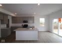 Bright kitchen featuring an island, stainless appliances, light gray cabinets, and hardwood floors at 17026 Cowbell Dr, Noblesville, IN 46060