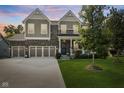 Charming two-story home at dusk featuring a three-car garage, brick accents, covered porch, and lush lawn at 4285 Nottinghill Dr, Avon, IN 46123