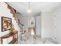 Bright foyer with a marble floor, a wooden staircase, and a decorative half-round table at 5917 Camelback Ct, Indianapolis, IN 46250