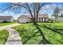 Inviting ranch-style home with lush lawn, long driveway and mature tree casting shadow on the grass at 6026 Sally Ann Cir, Indianapolis, IN 46237