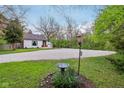 Long gravel driveway leading to a well-maintained home with a quaint birdbath in a serene setting at 6481 Michigan Rd, Indianapolis, IN 46268