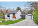 Charming home with bright orange door, black trim, and attached garage, surrounded by lush greenery at 6481 Michigan Rd, Indianapolis, IN 46268