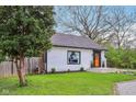 White home with a striking orange door and manicured lawn offers a fresh and inviting curb appeal at 6481 Michigan Rd, Indianapolis, IN 46268