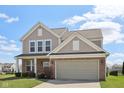 Charming two-story home with brick and vinyl siding, complemented by a well-manicured lawn at 6681 Keepsake Dr, Whitestown, IN 46075