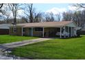 Ranch home with a carport, featuring a brick facade, green lawn, and mature trees at 838 Highland Dr, Whiteland, IN 46184