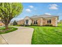 Lovely single-story brick home with a well-kept lawn, mature trees, and a welcoming driveway at 958 Tamarack Cir N Dr, Indianapolis, IN 46260