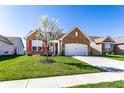 Charming brick home featuring a well-manicured lawn, blossoming tree, and attached two-car garage, all under a clear blue sky at 1371 Blackthorne N Trl, Plainfield, IN 46168