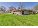 Ranch-style home with stone exterior, mature trees, and sprawling green lawn at 2329 E 8Th St, Anderson, IN 46012