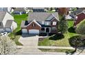Expansive aerial view of a two-story home with an attached garage, lush green lawn, and mature trees at 5145 Greenheart Pl, Indianapolis, IN 46237