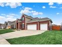 Spacious three-car garage and long driveway, brick accents, and well-kept lawn contribute to curb appeal at 8734 Blue Marlin Dr, Indianapolis, IN 46239