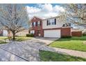 Attractive brick and siding home with a two-car garage and blossoming trees in the front yard at 10303 Memorial Knoll Dr, Indianapolis, IN 46234